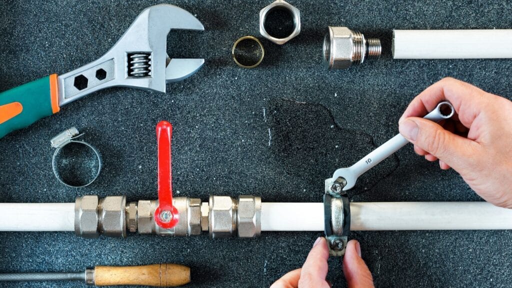 Plumber repairing a pipe valve with an adjustable wrench in Fontana