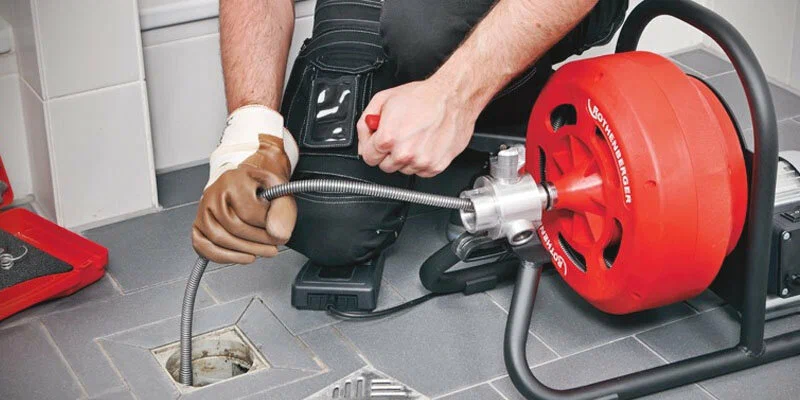 Plumber using a drain-cleaning machine in Fontana