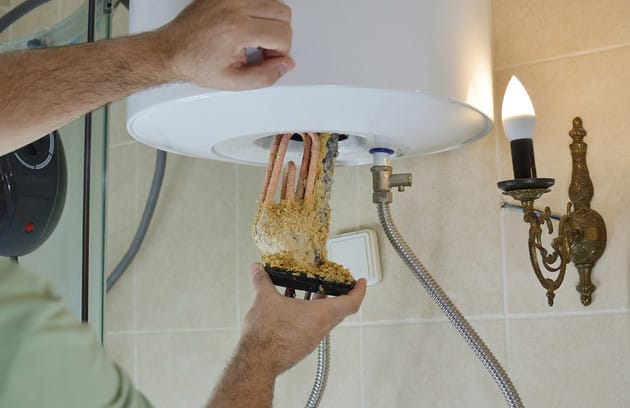 Technician removing mineral buildup from a water heater in Fontana