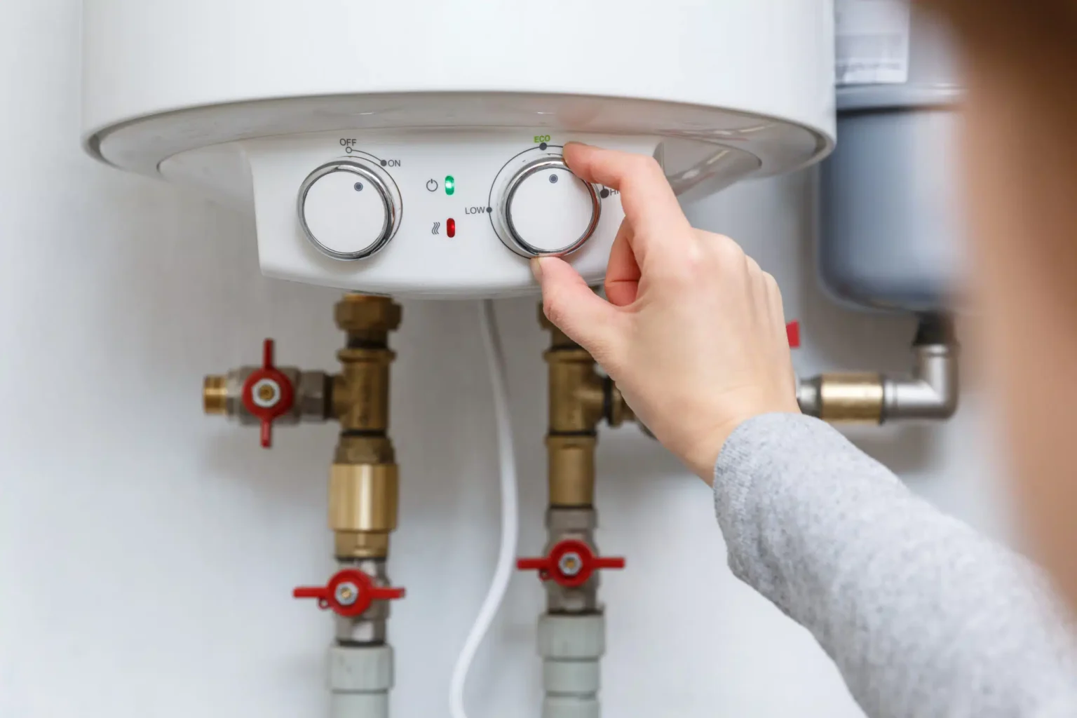Homeowner adjusting the temperature controls on a water heater in Fontana